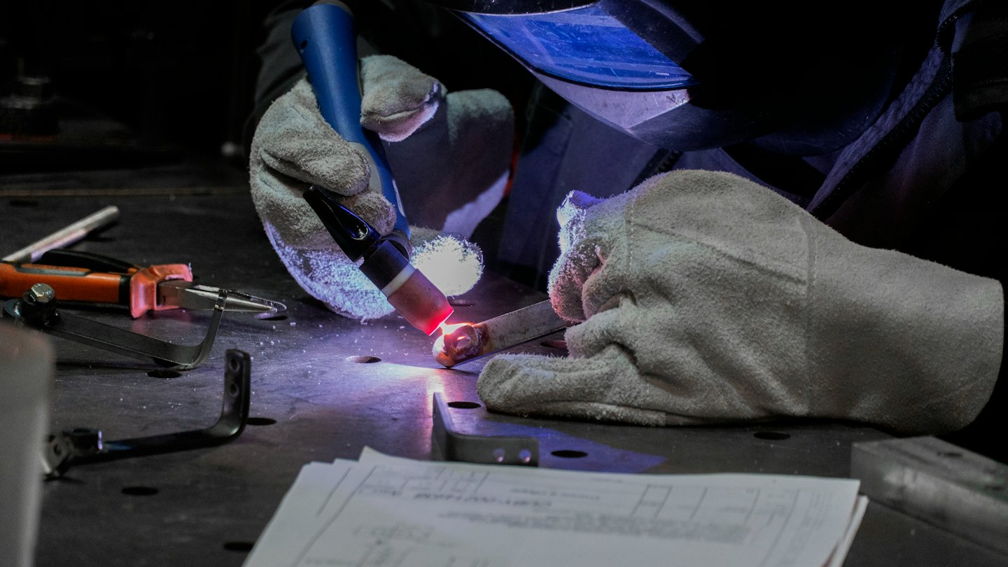 Welder using TIG torch to weld metal component.