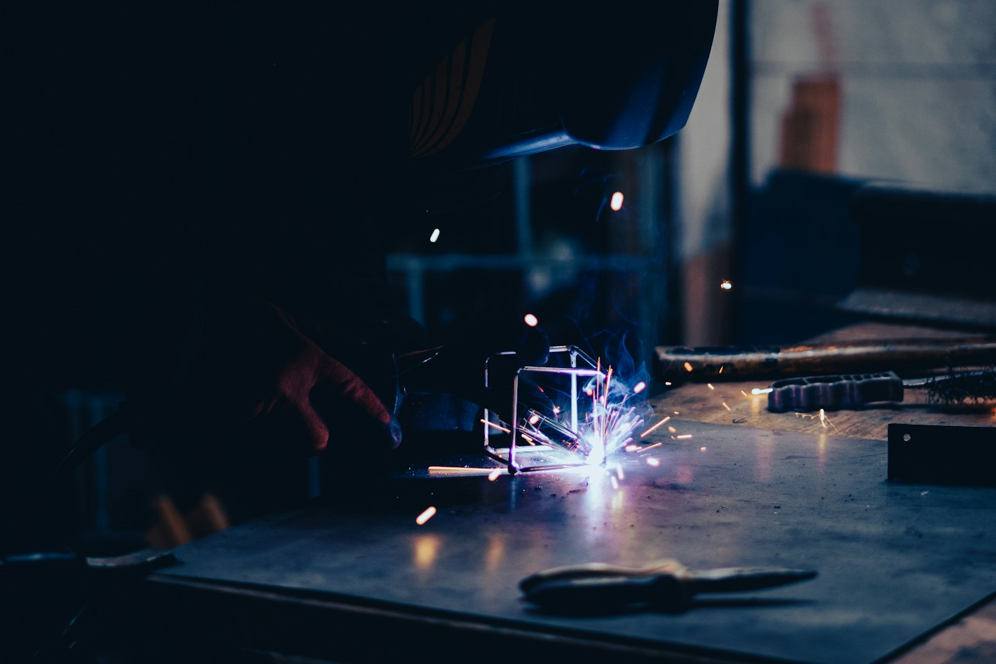 Welder working on metal structure in workshop.