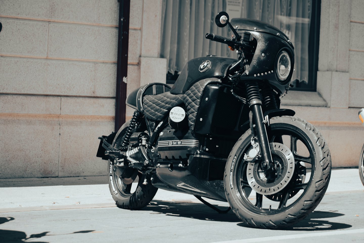 A black custom motorcycle parked on a paved street.