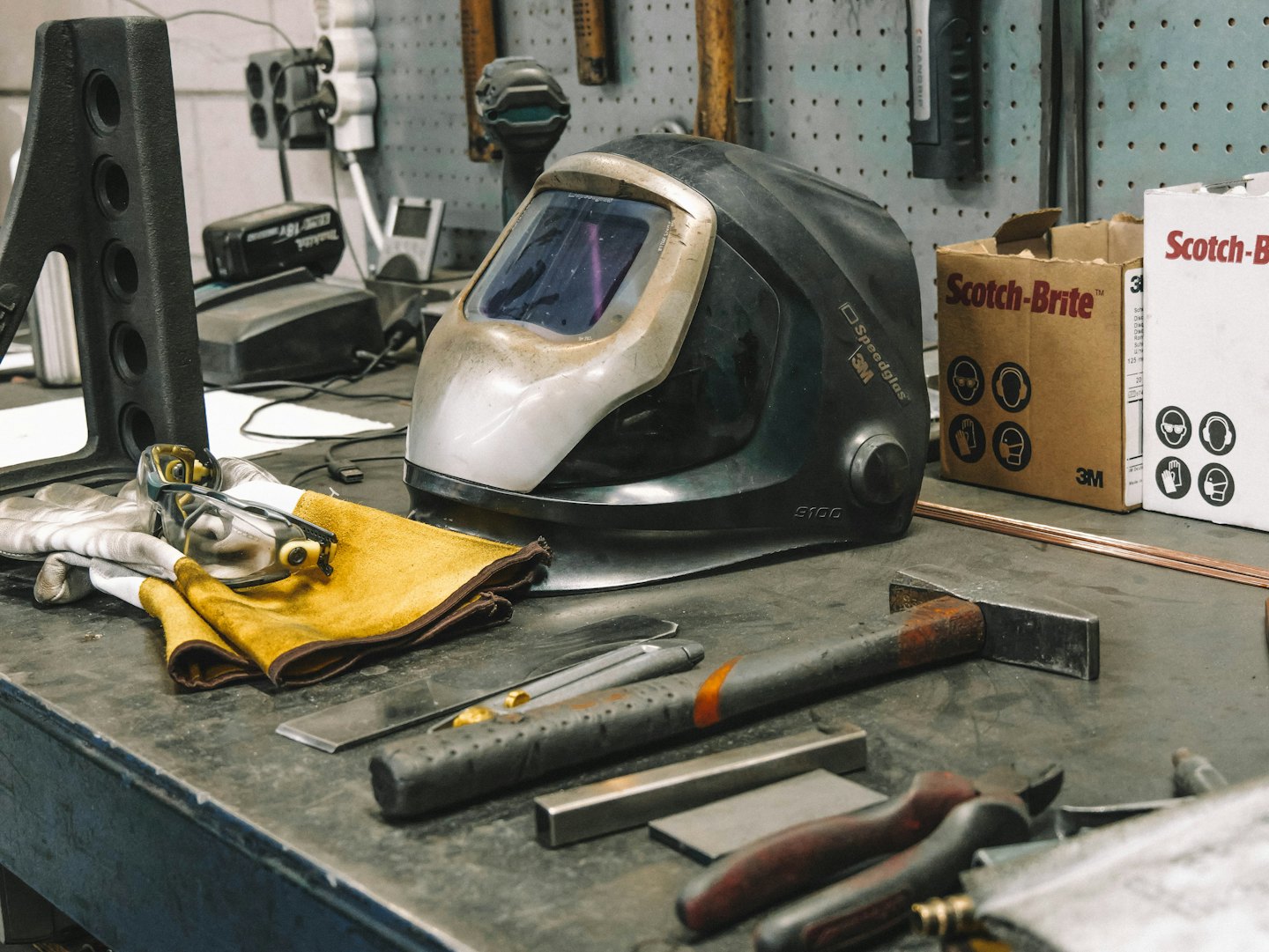 Welding helmet and tools on a workbench in a workshop.