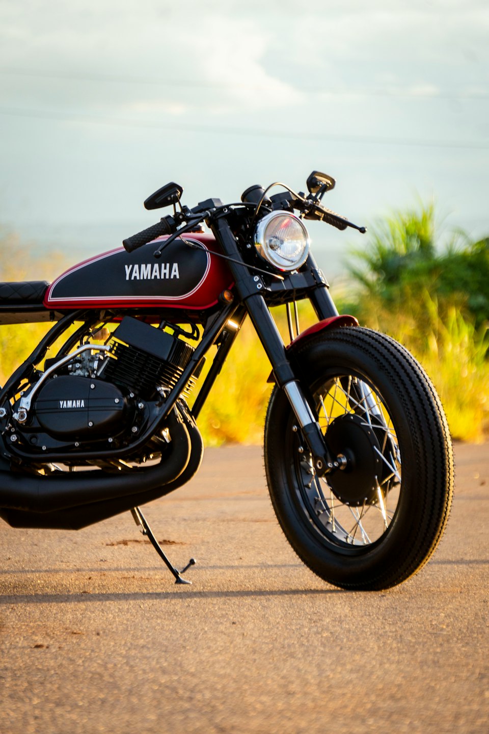 Custom vintage motorcycle with black and red tank parked on asphalt.